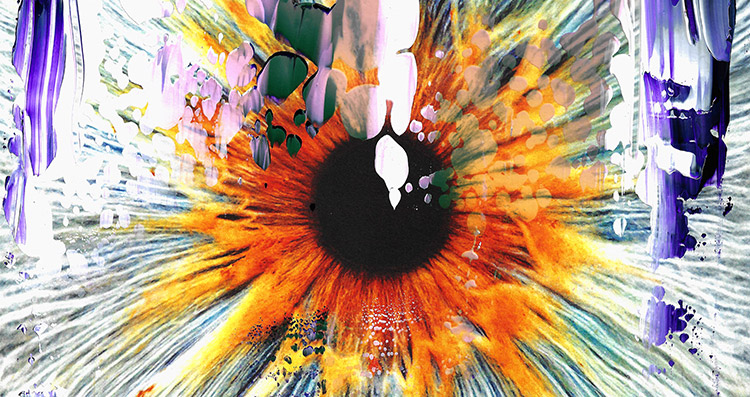 A close-up of an eye with a red-orange iris covered in colourful paint splatters.