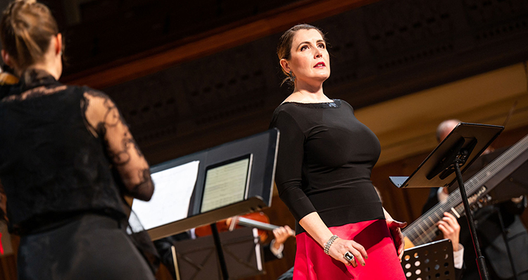 Close up of mezzo-soprano Krisztina Szabó performing on stage of Jeanne Lamon Hall with a violinist next to her.