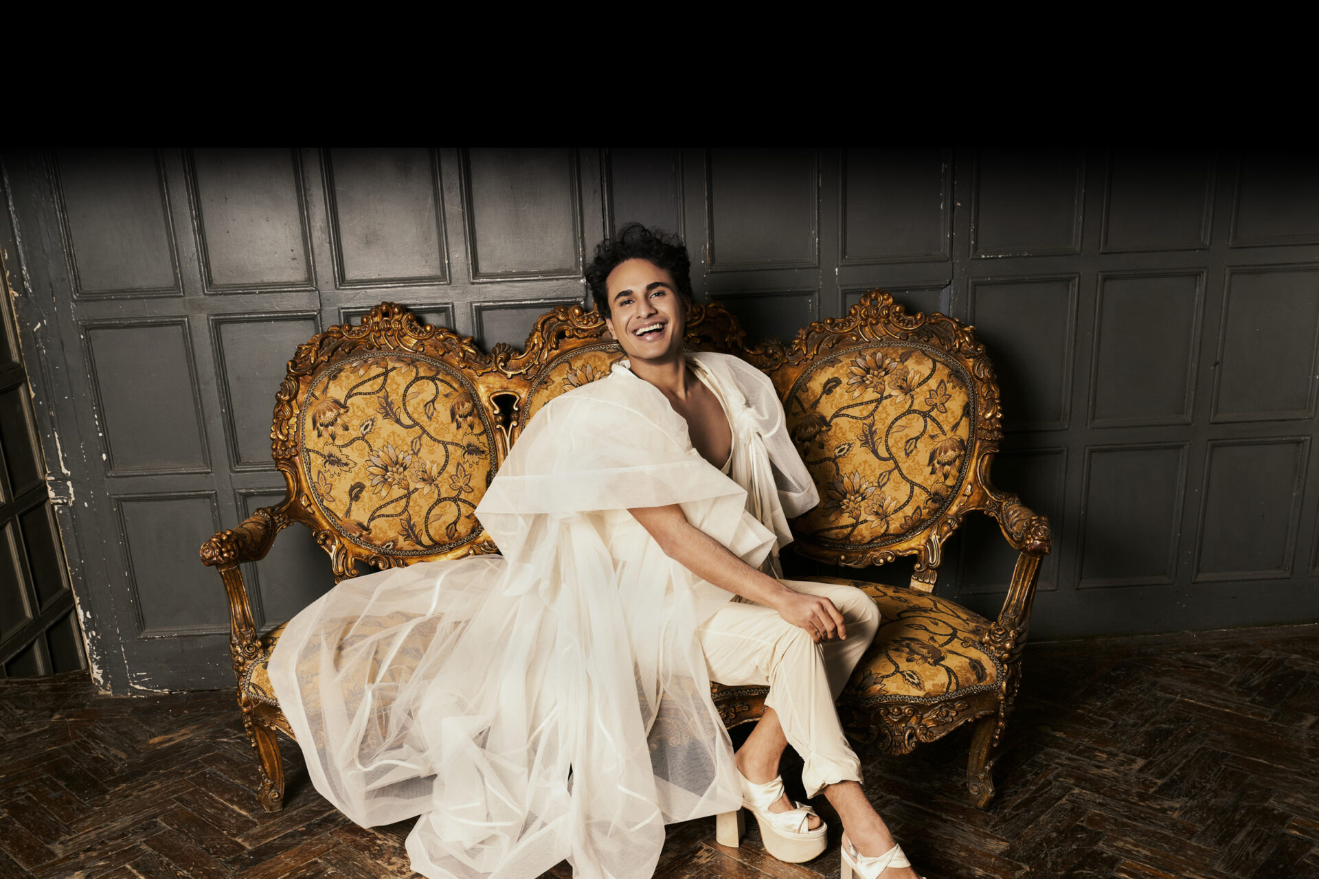 Image of Samuel in white dress on gold couch
