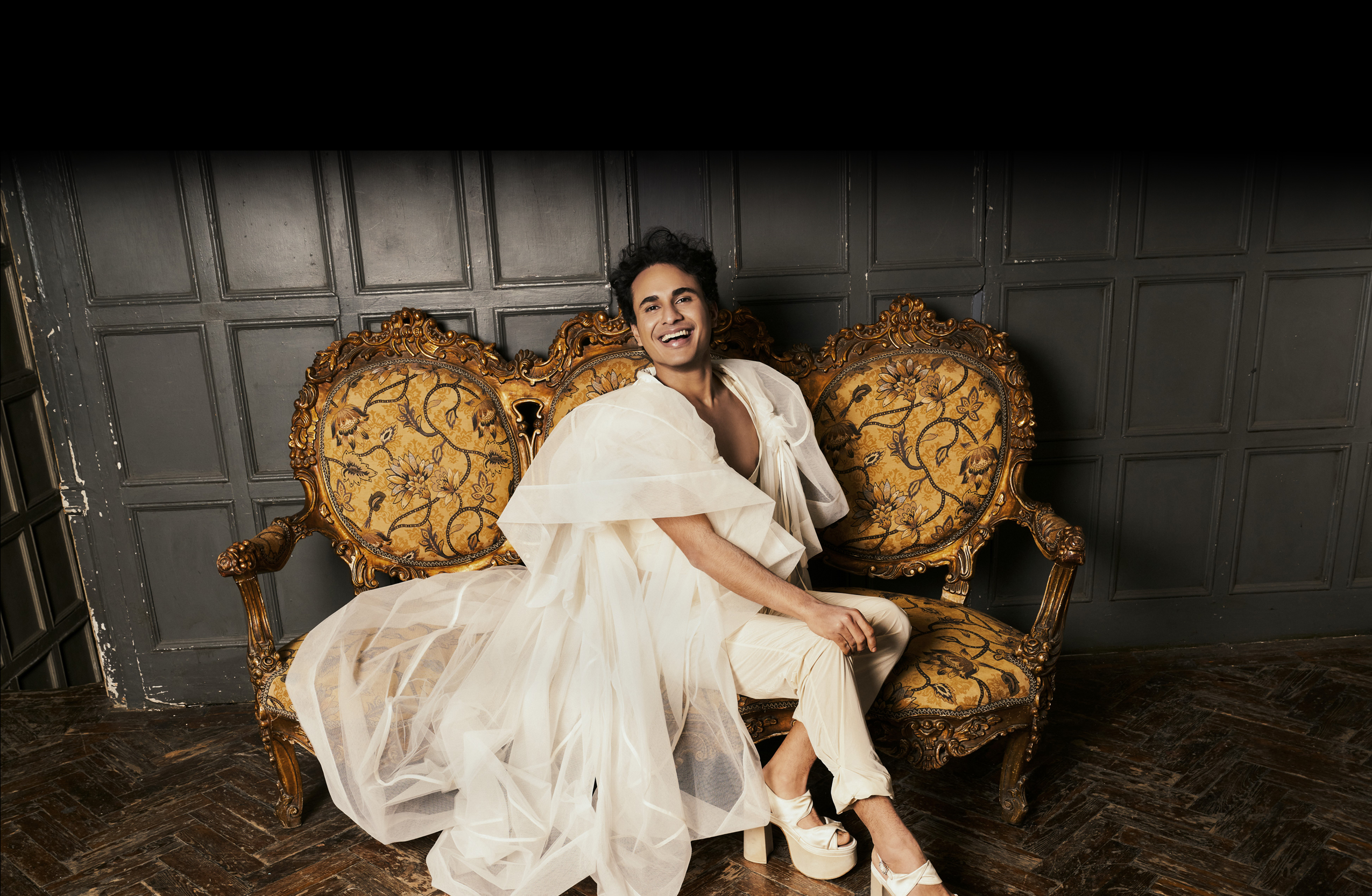 Image of Samuel in white dress on gold couch