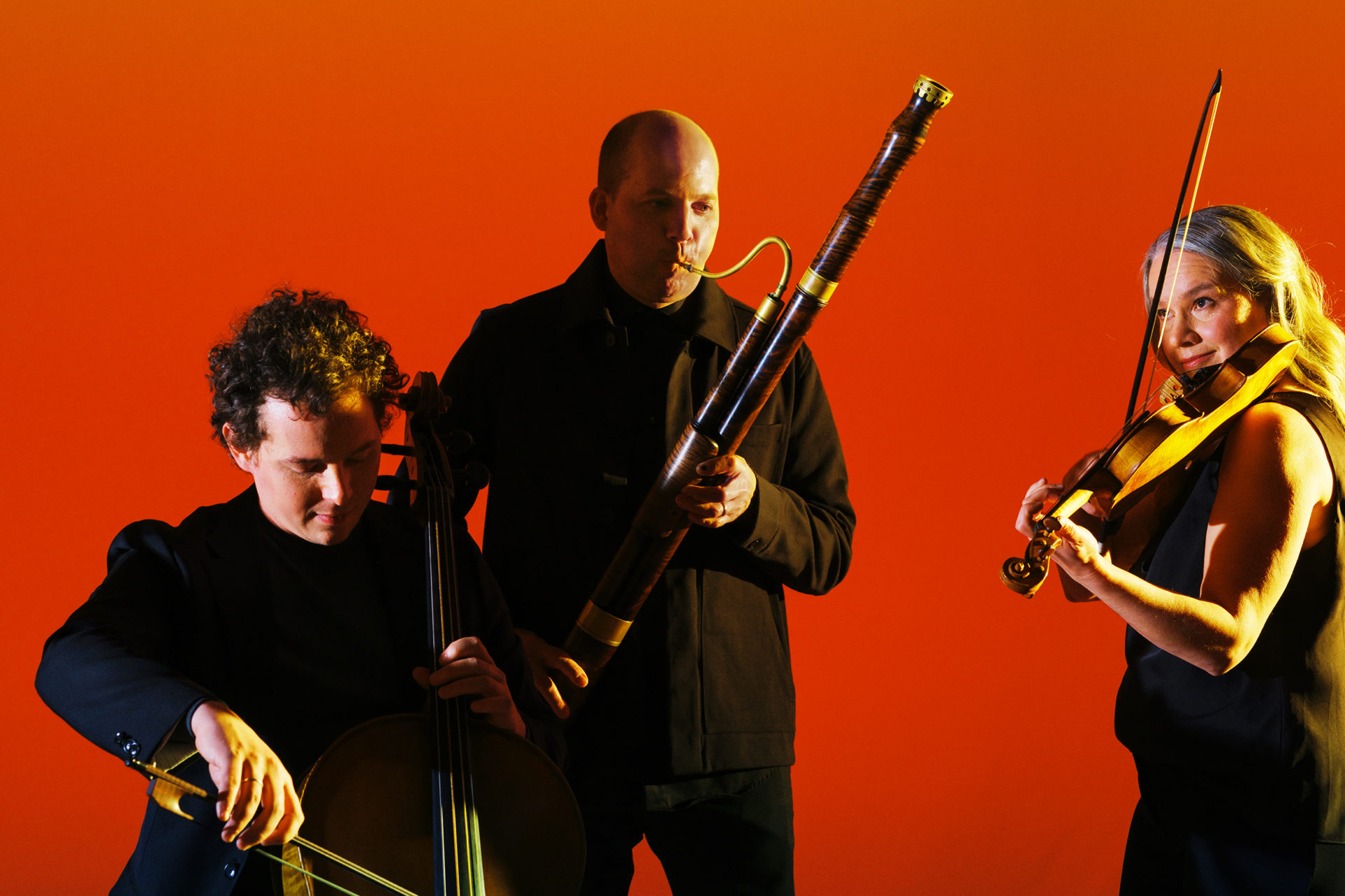 Musicians posing with their instruments in a studio with a warm glow