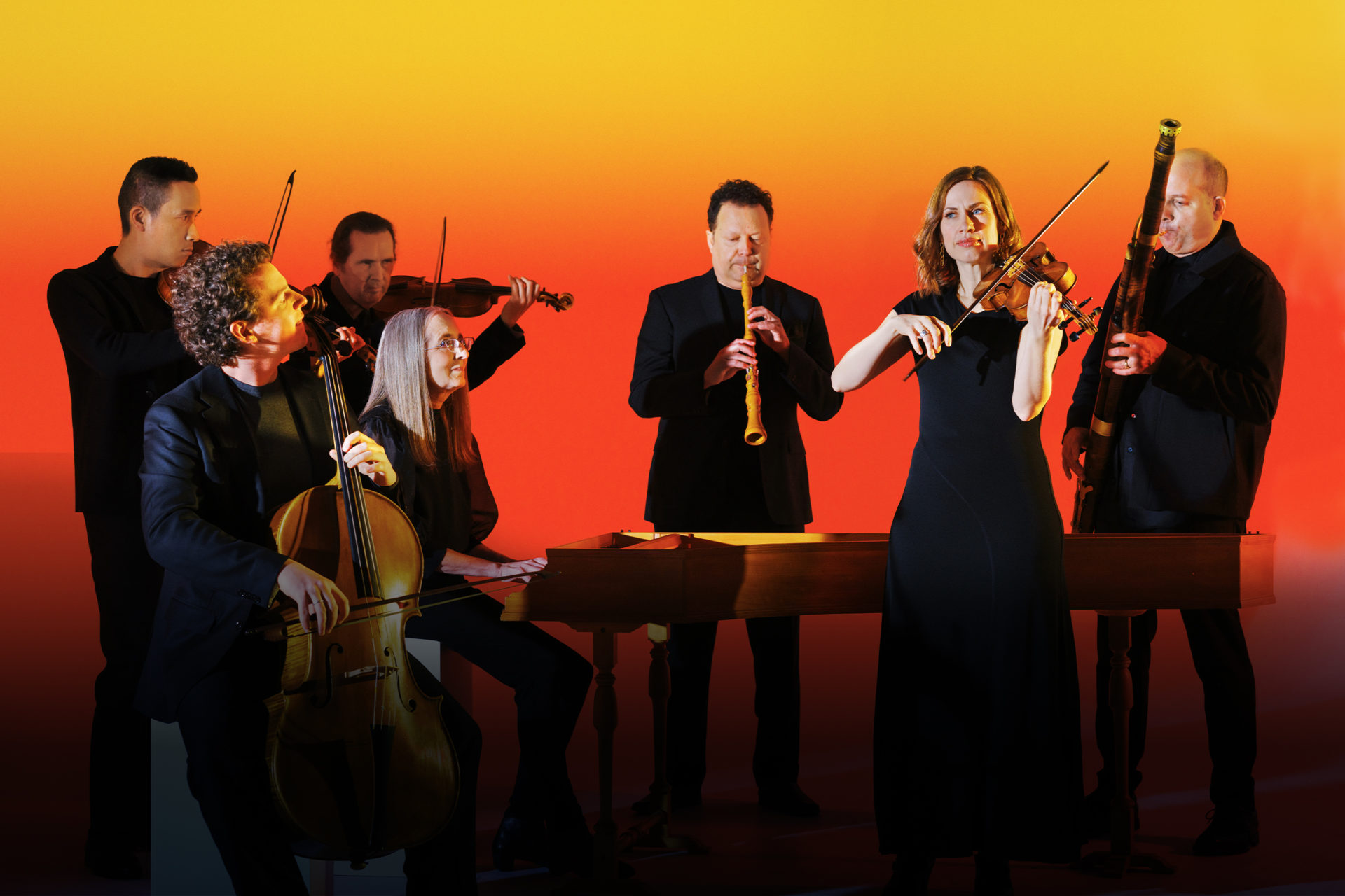 Musicians posing with their instruments in a studio with a warm glow