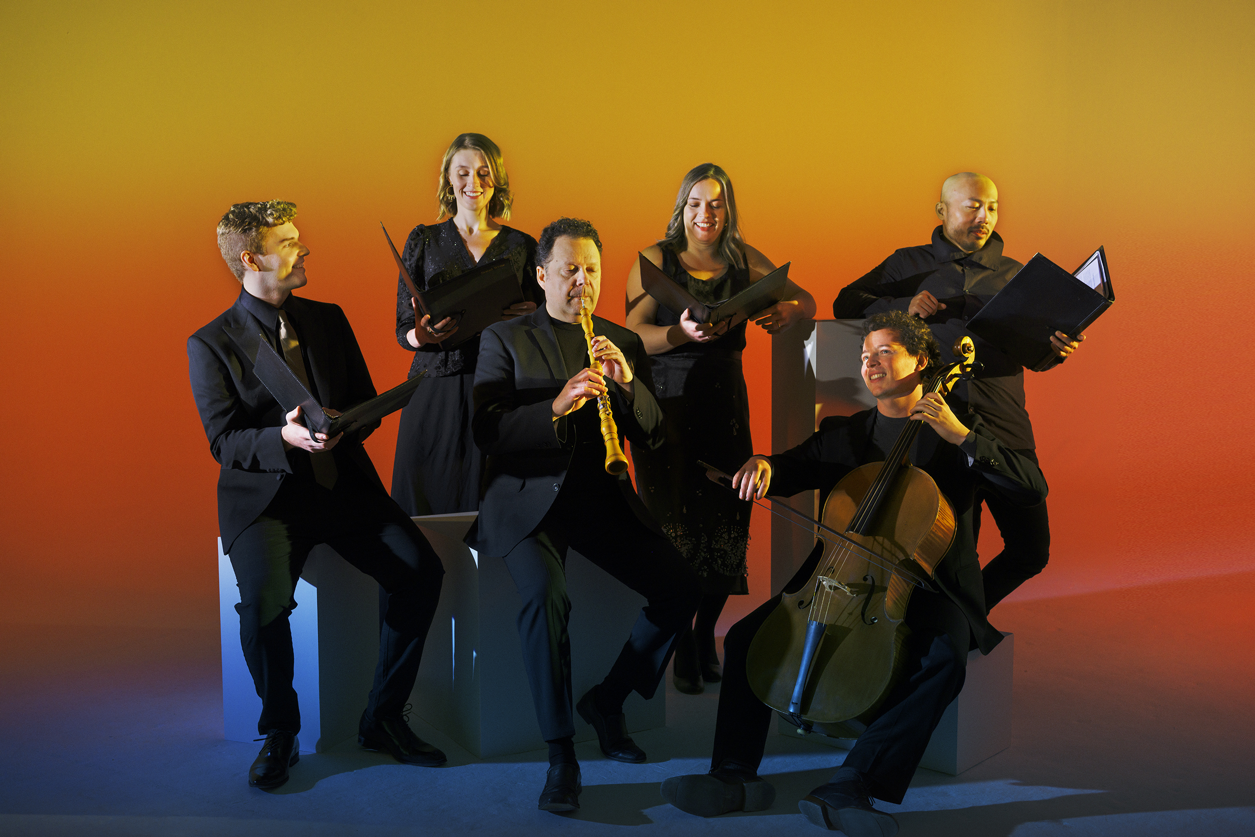 Musicians posing with their instruments in a studio with a warm glow