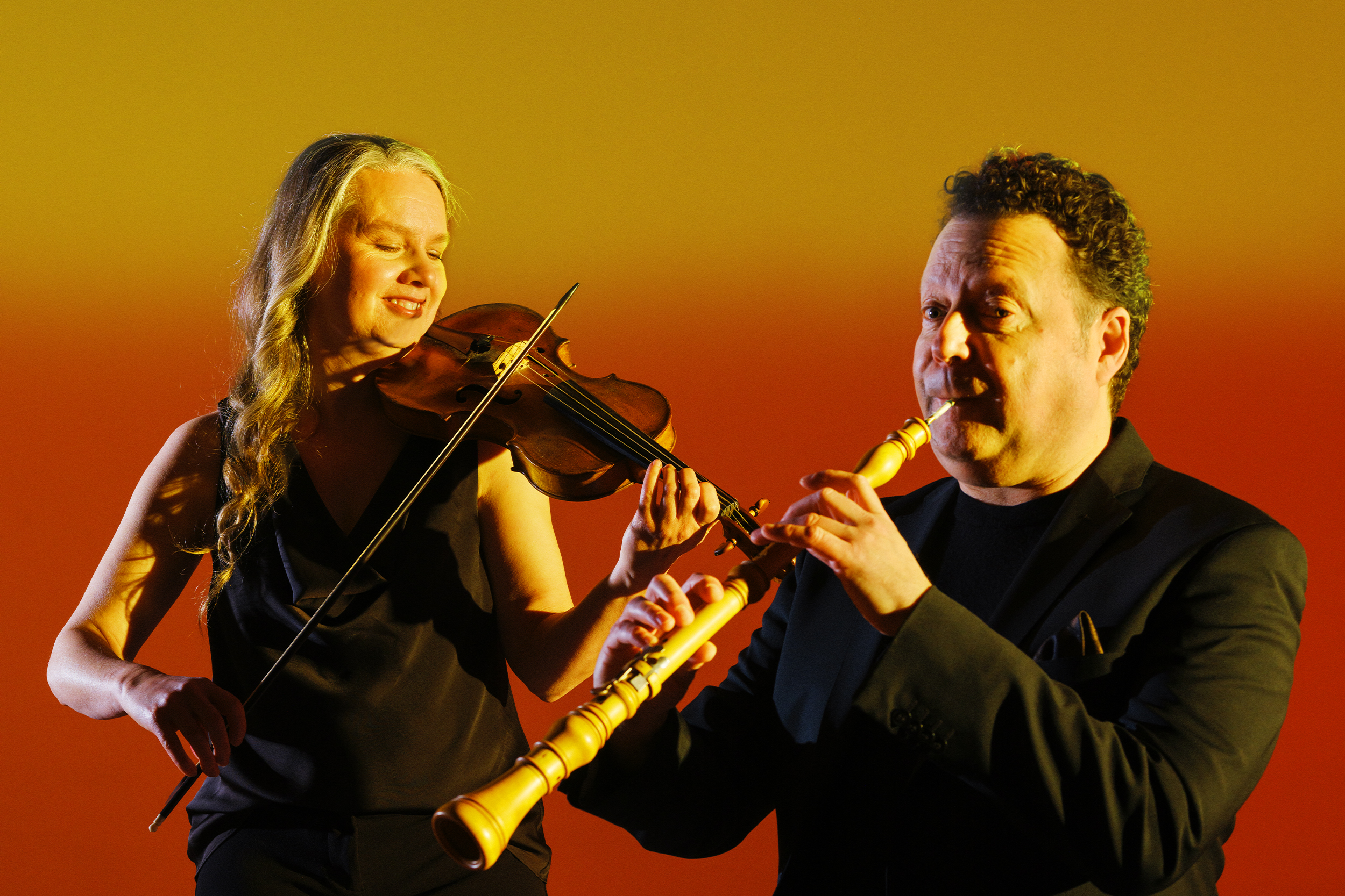 A violinist and oboist perform in a warm studio