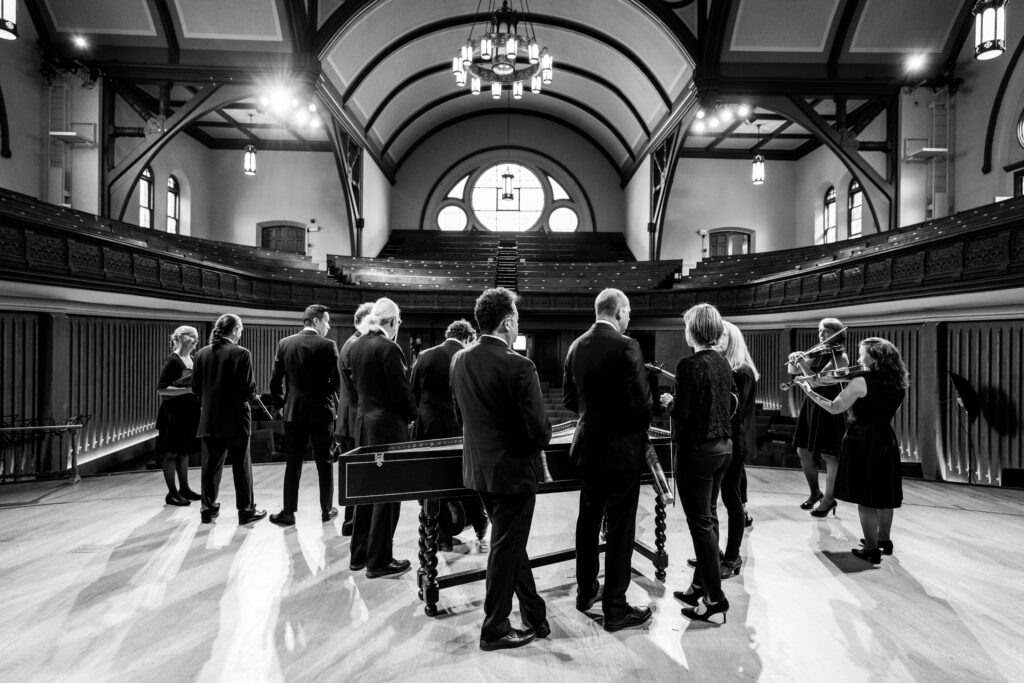 Black and white picture of Tafelmusik Orchestra pictured from behind, on our home venue stage