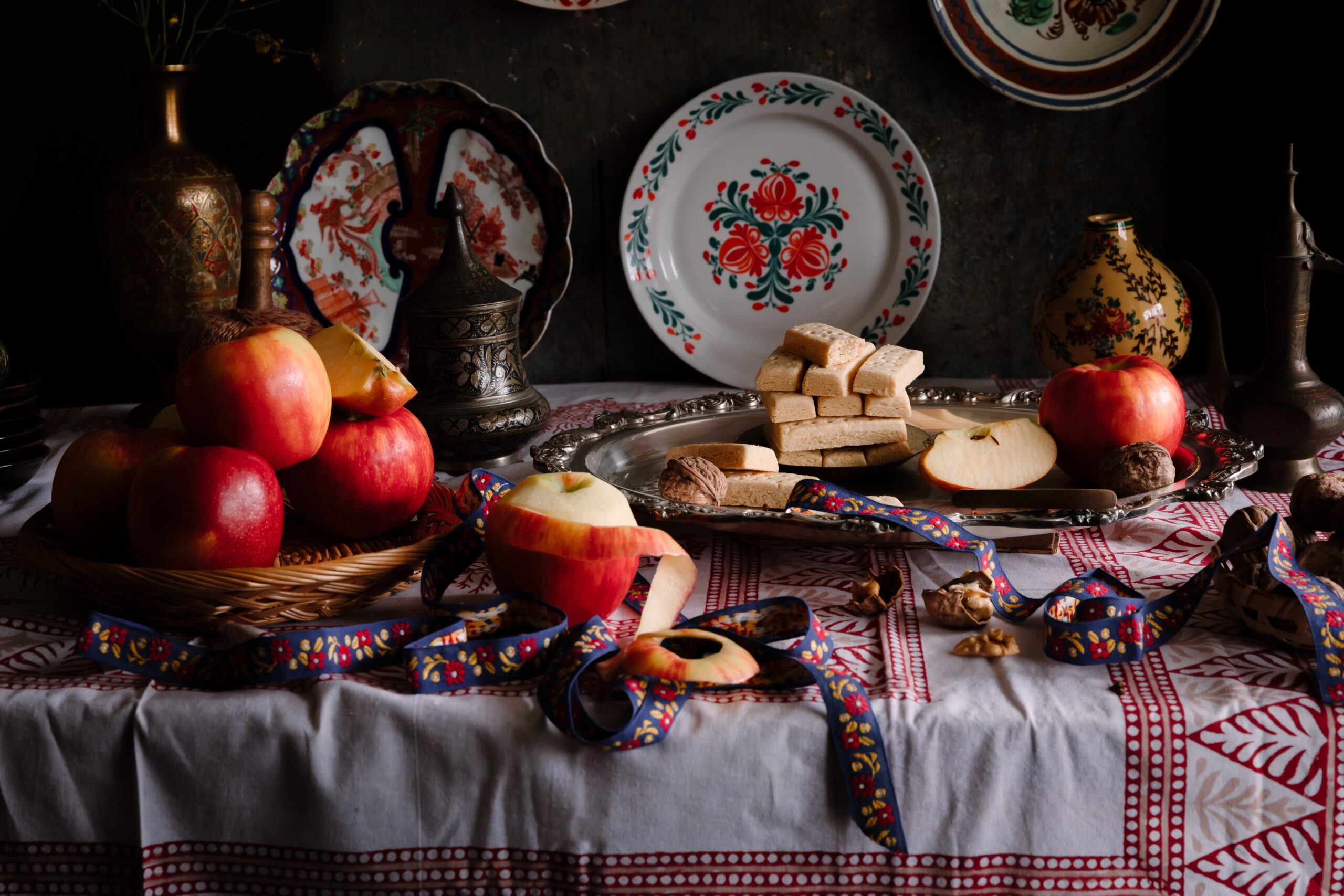 An image of apples, biscotti and plates on the table