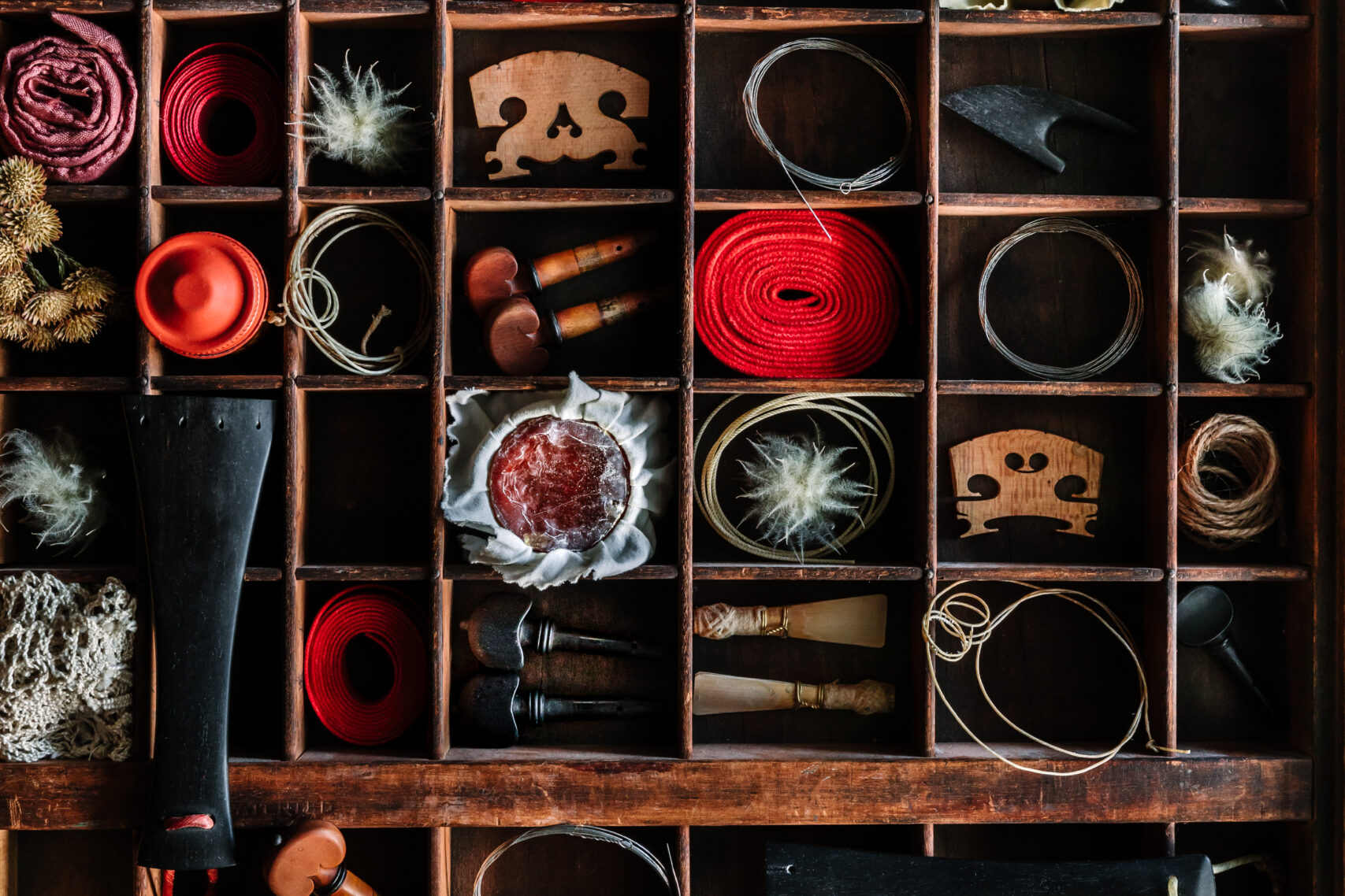 A shelf covering the whole wall with random objects, parts of instruments and yarn of wool