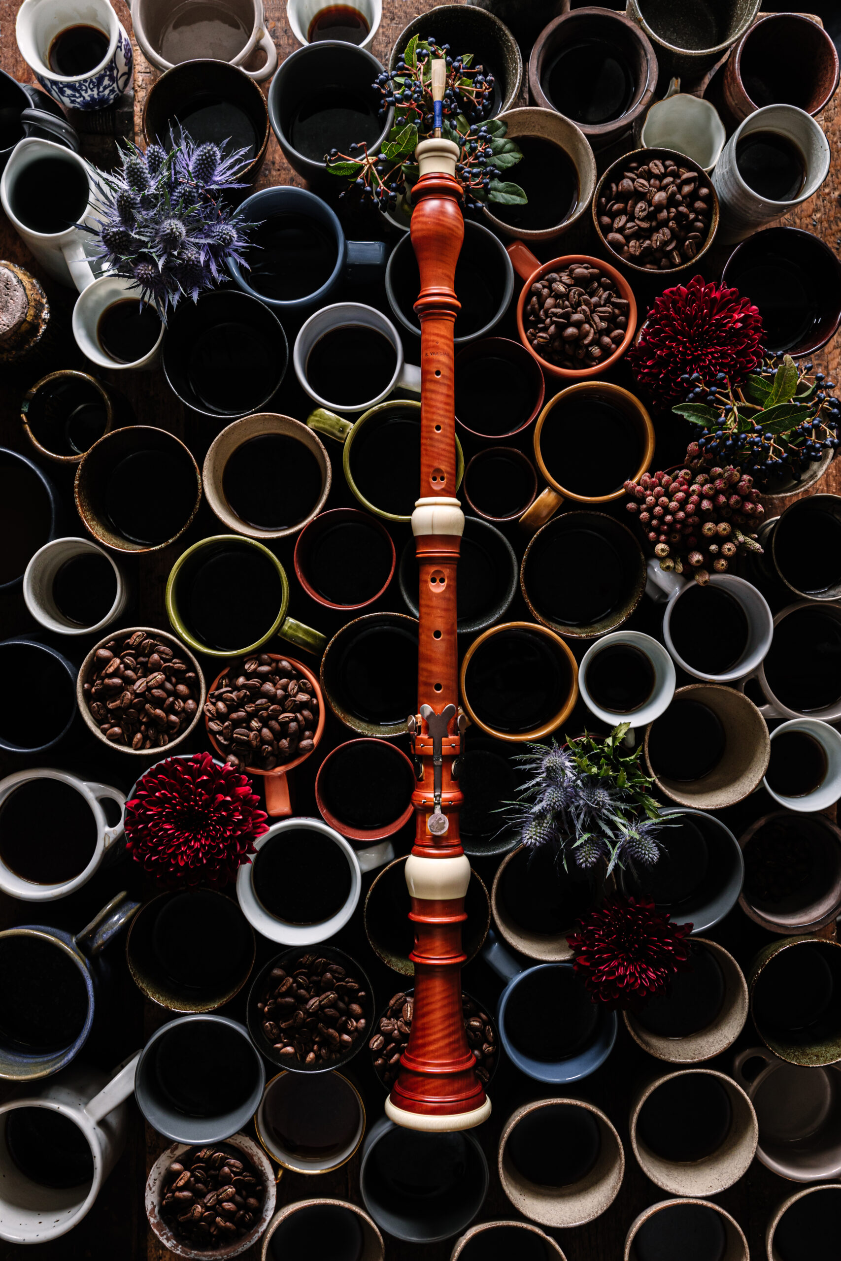 An image of random colourful mugs with a few of them filled with coffee beans and a bassoon placed on them vertically