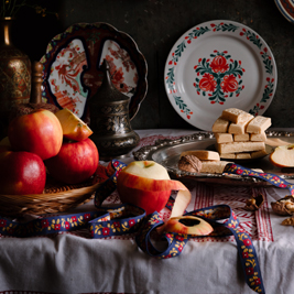 An image of apples, biscotti and plates on the table