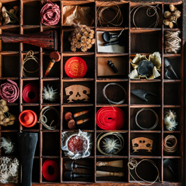 A shelf covering the whole wall with random objects, parts of instruments and yarn of wool