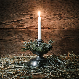 A candle burning on a pile of hay