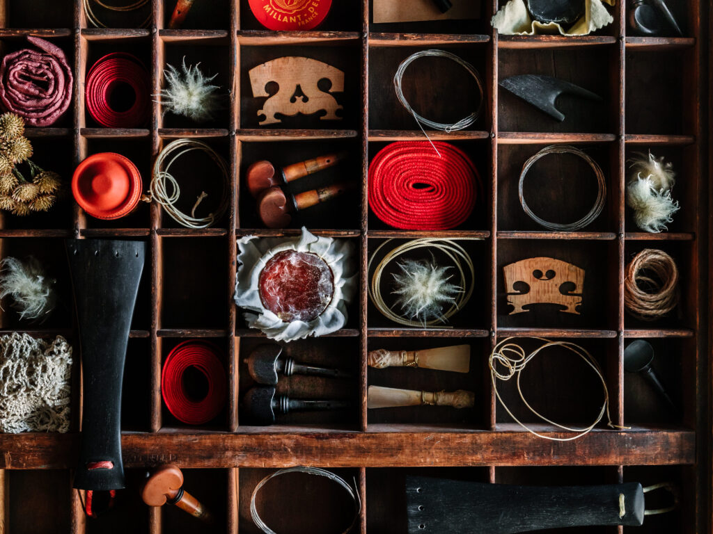 A shelf covering the whole wall with random objects, parts of instruments and yarn of wool