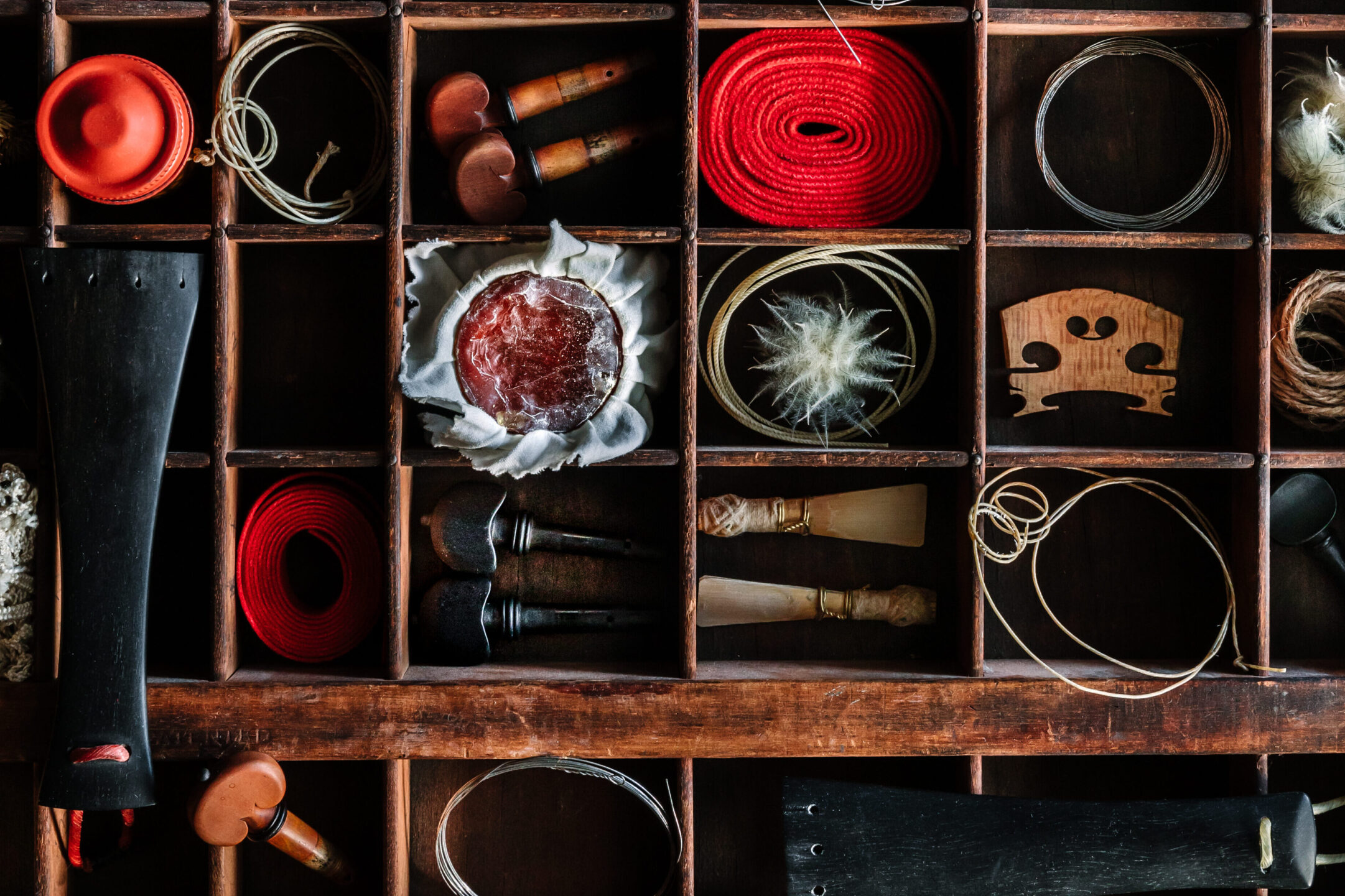 A shelf covering the whole wall with random objects, parts of instruments and yarn of wool